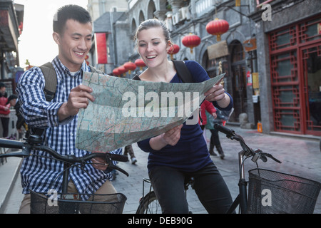 Jeune homme et femme sur les bicyclettes, en regardant la carte. Banque D'Images