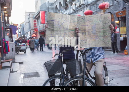 Jeune homme et femme sur les bicyclettes holding des cartes. Banque D'Images