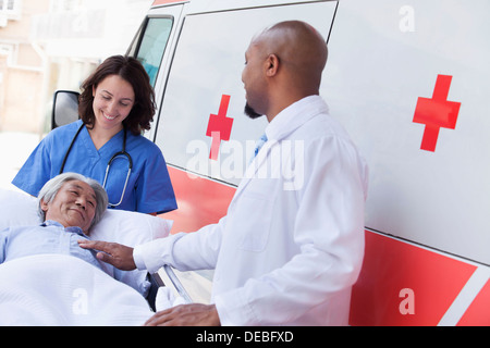 Médecin et paramédicaux, wheeling dans un patient âgé sur une civière dans une ambulance de l'avant Banque D'Images