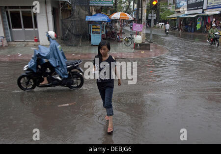 Tra Vinh, Tra Vinh, Vietnam. 16e Août, 2013. Comme d'habitude de vie qu'un café server marche à travers la rue, mouillés par une averse, d'offrir une boisson, septembre marque le début de la saison des pluies et selon AccuWeather.com forecuasts sont de bruine pluie ou orages chaque jour de la fin du mois. © Gary Dwight Miller/ZUMAPRESS.com/Alamy Live News Banque D'Images