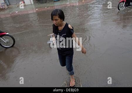 Tra Vinh, Tra Vinh, Vietnam. 16e Août, 2013. Comme d'habitude de vie qu'un café server marche à travers la rue, mouillés par une averse, d'offrir une boisson, septembre marque le début de la saison des pluies et selon AccuWeather.com forecuasts sont de bruine pluie ou orages chaque jour de la fin du mois. © Gary Dwight Miller/ZUMAPRESS.com/Alamy Live News Banque D'Images