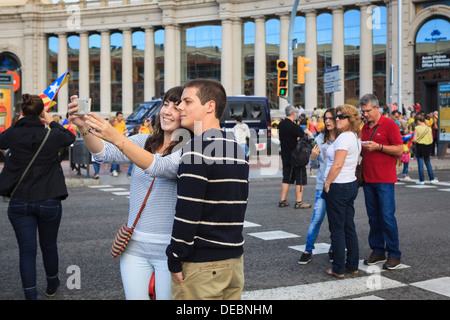 Couple taking self-portrait with mobile phone appareil photo en face de façon catalane. Barcelone. La Catalogne. L'Espagne. 11 septembre 2013. Banque D'Images