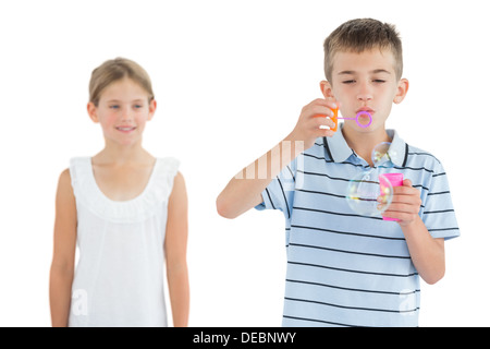 Garçon faire des bulles alors que sa sœur le regarder Banque D'Images