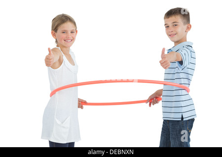 Happy brother and sister Playing with hula hoop giving Thumbs up Banque D'Images
