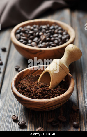 Le café moulu et les grains de café dans des bols sur fond de bois Banque D'Images