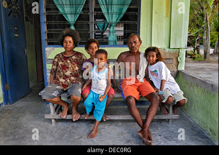 Famille assise sur un banc, Arborek, Raja Ampat, Papouasie occidentale, en Indonésie Banque D'Images