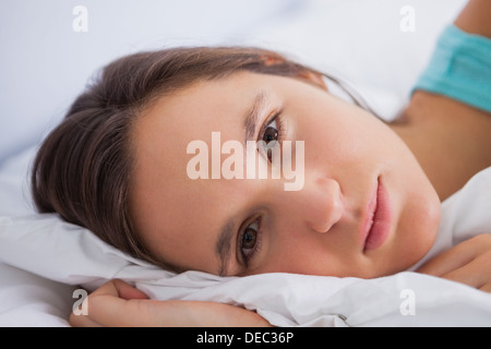 Femme couchée dans le lit à la recherche dans l'appareil photo Banque D'Images