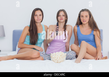 Girls sitting on bed at sleepover Banque D'Images