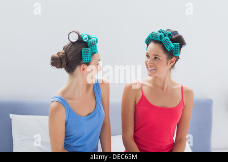 Girls wearing hair rollers sitting in bed Banque D'Images