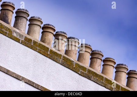 Une ligne de 11 pots de cheminée sur une cheminée de blancs se détachent sur un ciel bleu. Banque D'Images