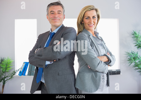 Deux heureux businesspeople looking at camera debout dos à dos Banque D'Images