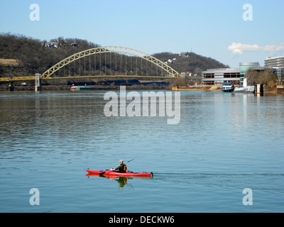 Un canoéiste pagaie le long de la rivière Allegheny à Pittsburgh, près de la confluence avec la rivière Monongahela à la fourche de l'Ohio, un monument historique. Le premier pont traversant la rivière Ohio est visible en arrière-plan. Banque D'Images