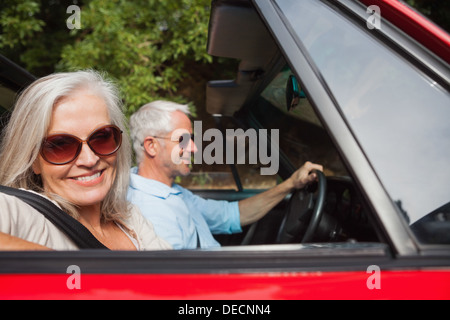 Vue latérale du smiling mature woman driving red cabriolet Banque D'Images