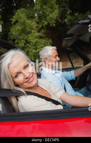 Vue de côté mature woman driving red cabriolet Banque D'Images