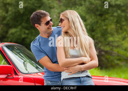 Cheerful young couple hugging et appuyé contre cabriolet Banque D'Images