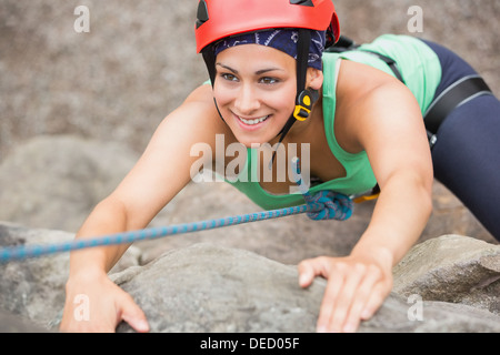 Happy girl climbing rock face Banque D'Images