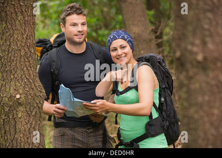 Monter couple reading map in a forest with woman pointing Banque D'Images