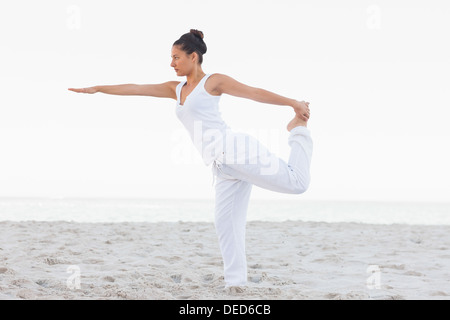 Brunette woman wearing tout blanc qui s'étend en yoga pose Banque D'Images