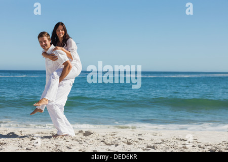 Smiling woman sitting on mans back and looking at camera Banque D'Images