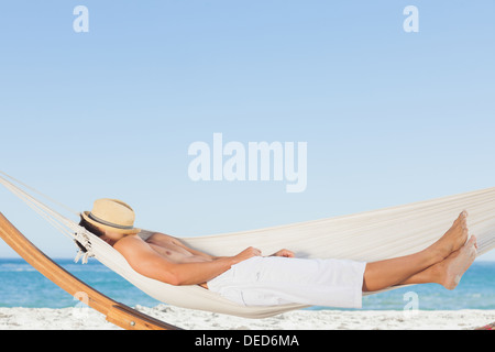 Man wearing straw hat relaxing in a hammock Banque D'Images