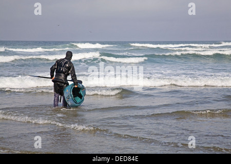 Un kayakiste se prépare à monter le surf sur la côte de l'Oregon, près de la côte de l'Oregon. Yachats Banque D'Images