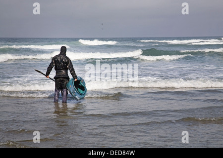 Un kayakiste se prépare à monter le surf sur la côte de l'Oregon, près de la côte de l'Oregon. Yachats Banque D'Images