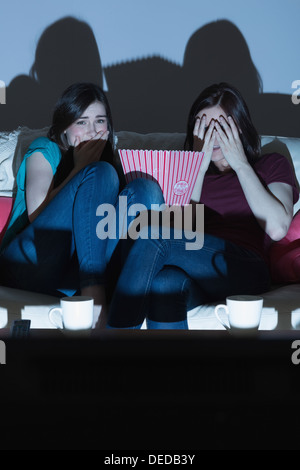 Deux amis sur le canapé à regarder un film d'horreur ensemble dans le noir Banque D'Images