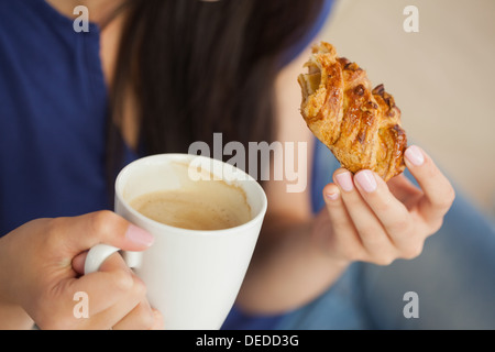Femme ayant une pâtisserie avec une tasse de café Banque D'Images