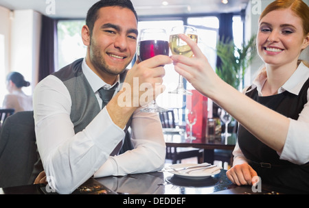 Smiling business partners tintement des verres à vin looking at camera Banque D'Images