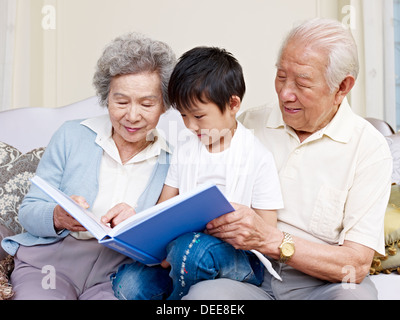 Les grands-parents et petit-fils de lire un livre ensemble. Banque D'Images