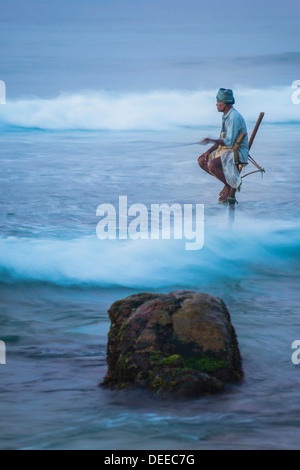 Pêche à échasses, un pêcheur sur pilotis dans les vagues à Midigama près de Weligama, Côte Sud, Sri Lanka, de l'Océan Indien, l'Asie Banque D'Images