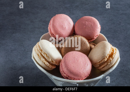 Framboise/fraise, vanille et chocolat macarons à la française aromatisée dans un bol Banque D'Images