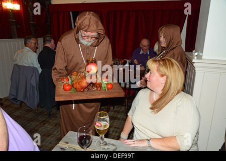 Moine avec tête de cochon de lait à la fête médiévale de la nuit, le Wheatsheaf pub, Crick, Northamptonshire, Angleterre, Royaume-Uni Banque D'Images