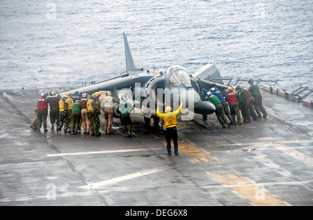 Marins et soldats US Marine Corps déplacer un AV-8B Harrier II aéronefs pendant une tempête de pluie dans le poste de pilotage de l'assaut amphibie USS Boxer le 11 septembre 2013 en cours dans l'océan Pacifique le 11 septembre 2013. Le boxeur était en cours aux États-Unis 7e flotte domaine de responsabilité des opérations de sécurité maritime et les efforts de coopération en matière de sécurité dans le théâtre. Banque D'Images