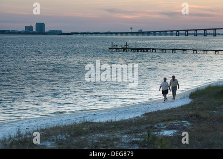 Couple à pied sur la plage de sable blanc de Santa Rosa Sound au crépuscule en Navarre, en Floride Banque D'Images