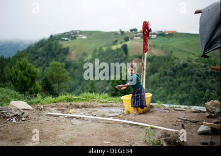 Une fille guatémaltèque en vêtements traditionnels Maya lave la vaisselle à l'extérieur de la région de Caserio Panuca, Solola, Guatemala. Banque D'Images