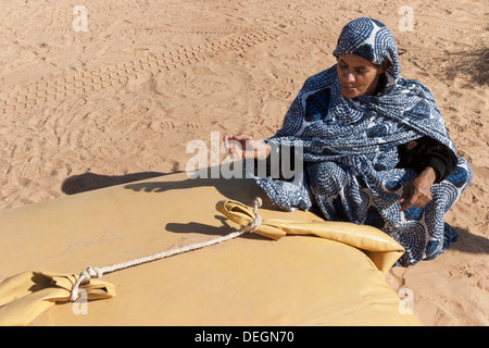 Femme de la famille nomade, portant le mulafa, robe traditionnelle mauritanienne, sur le point de prendre de l'eau dans la vessie de stockage dans la région de desert Banque D'Images