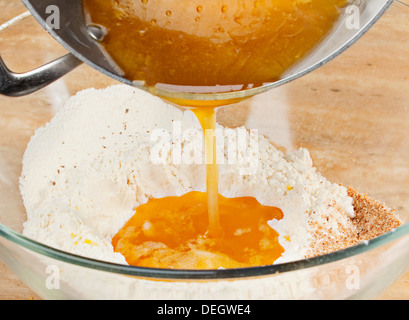 Ajouter le miel et le beurre fondu dans la farine Banque D'Images