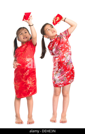 Heureux les filles asiatiques peeking en paquet rouge pendant le Nouvel An chinois, avec pleine longueur Cheongsam traditionnel article isolé sur fond blanc. Banque D'Images