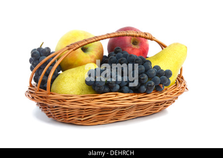 Poires mûres, les pommes et les raisins dans un panier en osier. Présenté sur un fond blanc. Banque D'Images