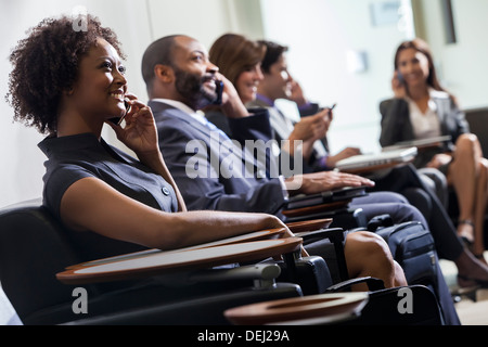 African American Woman ou businesswoman using cell phone in aéroport actif avec d'autres personnes en arrière-plan Banque D'Images
