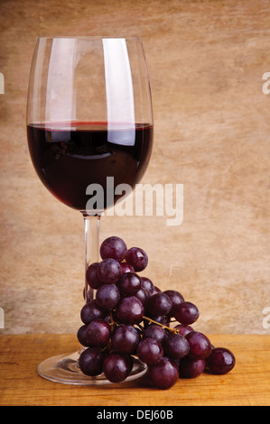 Verre de vin rouge et les raisins sur un fond de bois vintage Banque D'Images