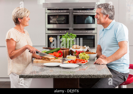 Man & woman couple préparation des sandwichs sains à la maison cuisine avec jambon, fromage, salade de laitue et tomates Banque D'Images