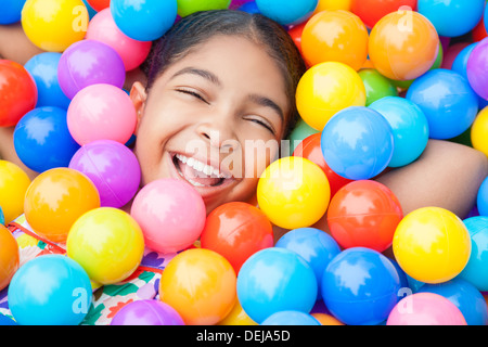 Happy African American girl enfant rire et jouer à des centaines de plastique colorés balles multicolores Banque D'Images