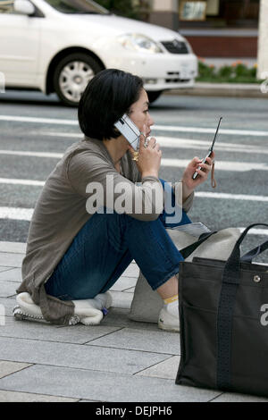 Tokyo, Japon. 20e Septembre, 2013. Une femme attend tôt le matin, en dehors d'Apple Store pour obtenir le nouveau smartphone, le 20 septembre 2013. Plus de sept cents personnes patiemment la queue tôt le matin avant l'Apple Store ouvre ses portes à Ginza. Le Japon est l'un des premiers pays où Apple fans pouvaient obtenir le nouvel iPhone 5s et moins chères de l'iPhone 5c. Credit : Rodrigo Reyes Marin/AFLO/Alamy Live News Banque D'Images