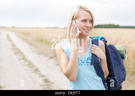 Les jeunes female hiker using mobile phone while standing on field Banque D'Images