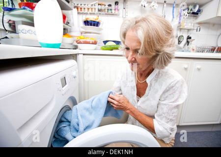 Senior woman loading lave-linge accueil Banque D'Images