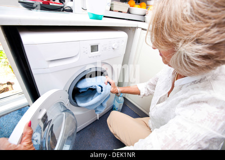 Senior woman loading accueil lave-linge sèche-serviettes Banque D'Images