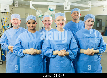 L'équipe médicale médecins chirurgiens interracial hommes femmes hôpital salle d'opération, le port de gants chirurgicaux gommages à heureux Banque D'Images