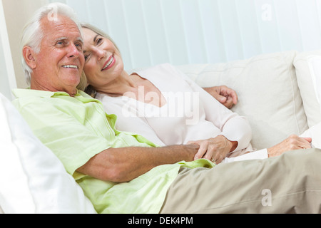 Happy senior man and woman couple assis ensemble à la maison en souriant et heureux Banque D'Images